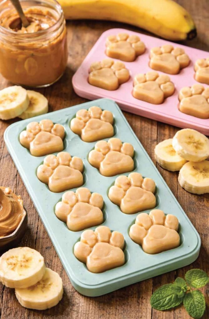 Homemade frozen peanut butter and banana dog treats in paw-shaped molds